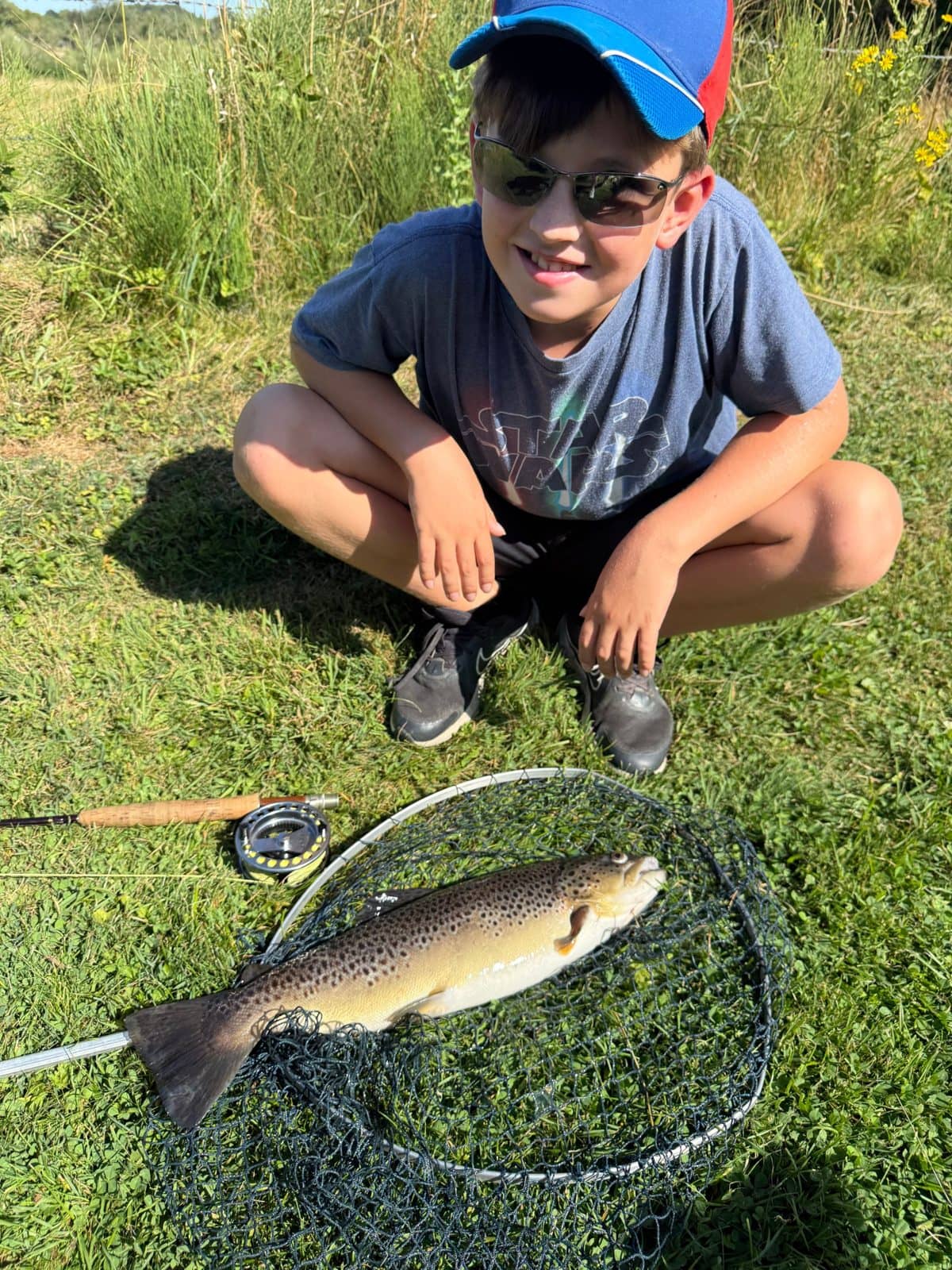 A young angler with a brown trout in a landing net