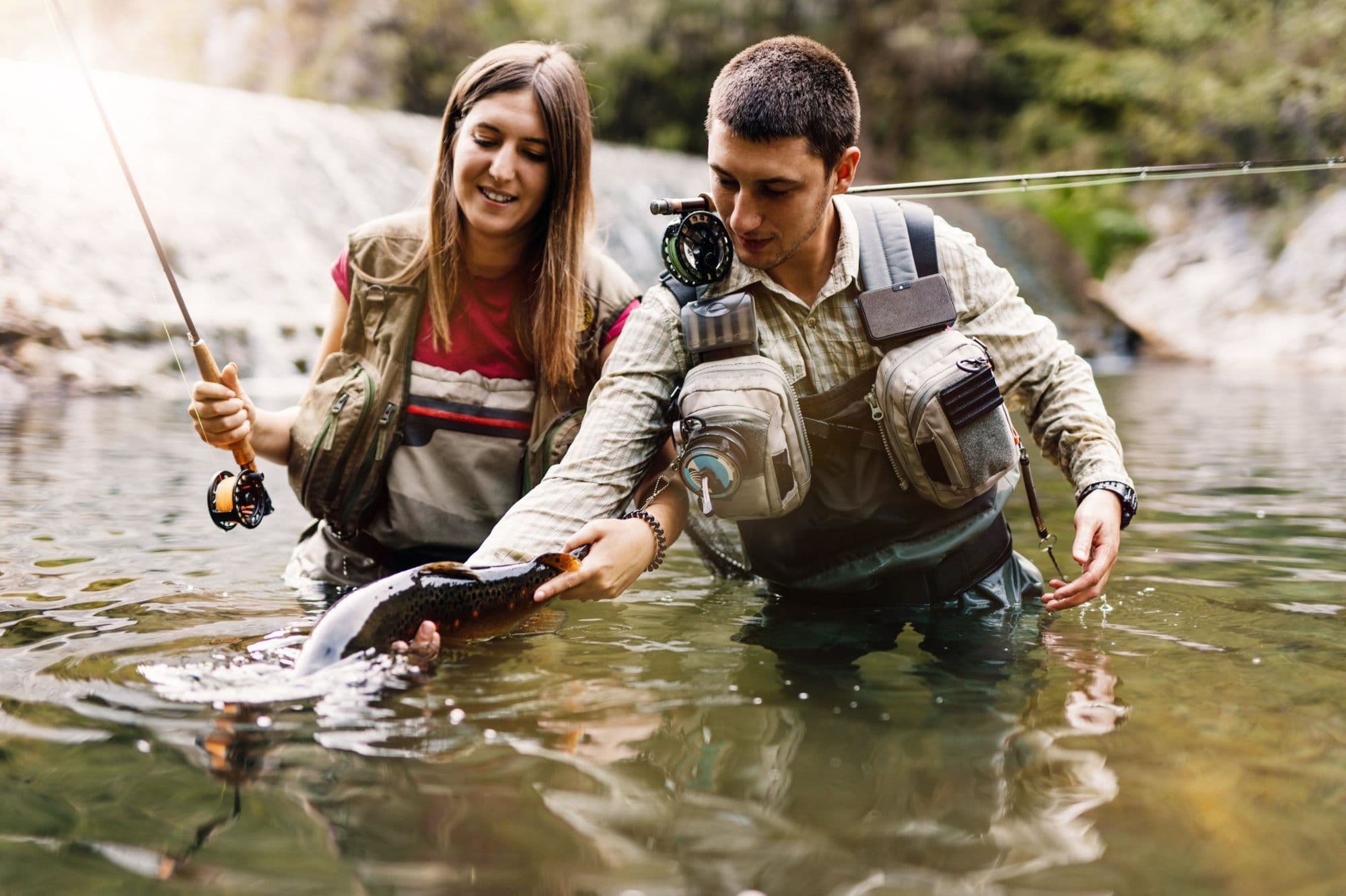 A guide and an angler releasing a trout together