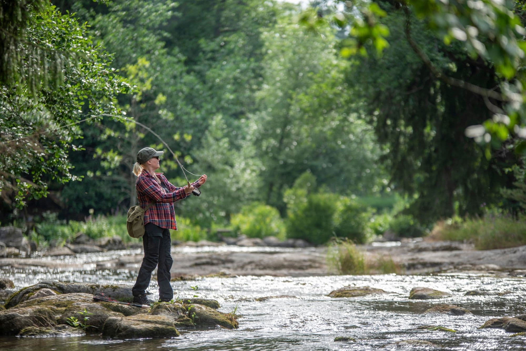 A woman casting a fly rod on a river